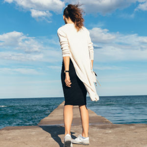 Kobieta w swetrze stojąca na molo